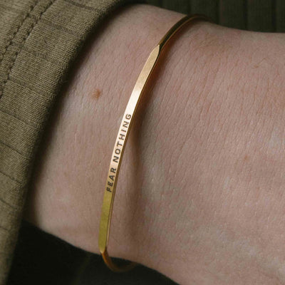 Gold bangle bracelet with the inspirational message “FEAR NOTHING” engraved on it.