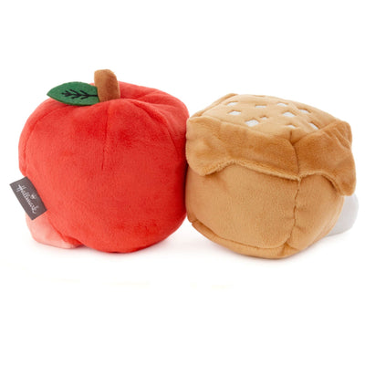 Two plush apples with attached leaves. One apple is red and one is green. They are connected by a brown fabric vine.