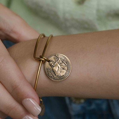 Gold bangle bracelet with a St. Raphael medallion.