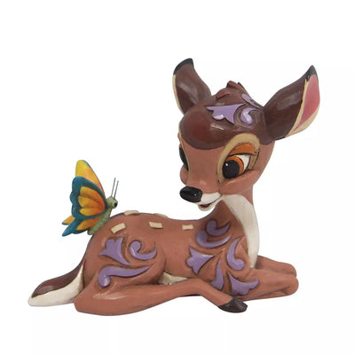 A cream colored ceramic figurine of a deer with a butterfly on its back
