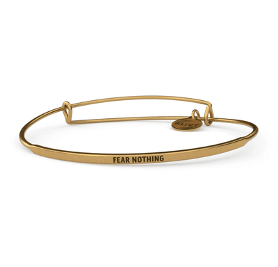 Gold bangle bracelet with the inspirational message “FEAR NOTHING” engraved on it.