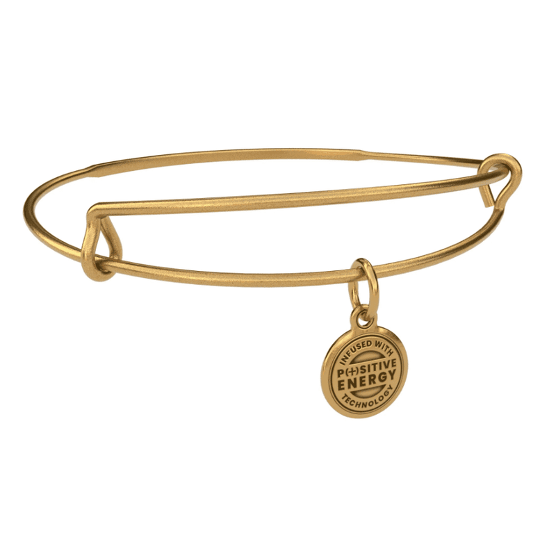 Gold bangle bracelet with a gold charm. The charm is round and features the text “ NFUSED WITH POSITIVE ENERGY TECHNOLOGY”