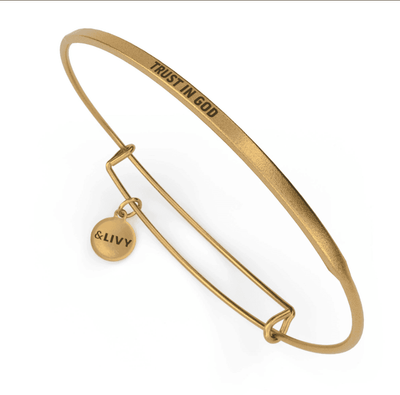 Gold bangle bracelet with the words "Trust in God" engraved on it.