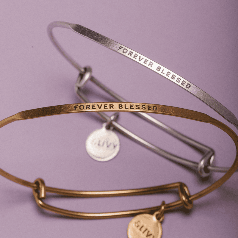 Gold bangle bracelet with the words "Forever Blesses" engraved on it.