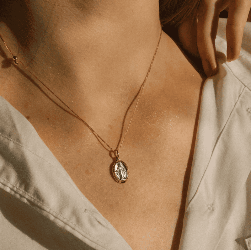 Gold necklace with a Miraculous Medal featuring the Virgin Mary.