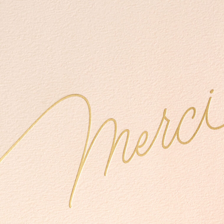 Blush pink thank-you cards with gold foil “Merci” script lettering and matching foil-lined envelopes in a white display box.
