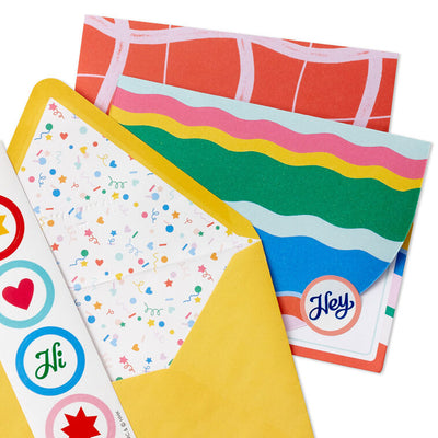 Stationery set with arched sheets in colorful wave and coral prints, yellow envelopes, and heart and star seal stickers.
