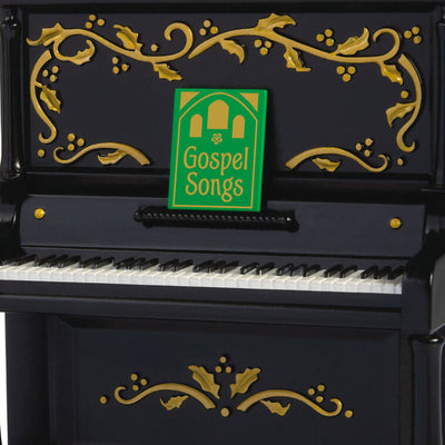 Upright Christmas piano ornament with gold holly accents, tinsel garland, and musical “I’ll Fly Away” gospel choir performa
