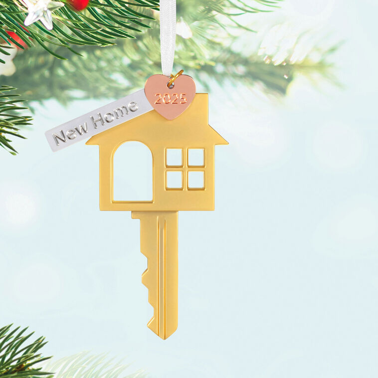 Gold metal key ornament shaped like a house with a pink heart and “New Home” banner charm, for new homeowners.