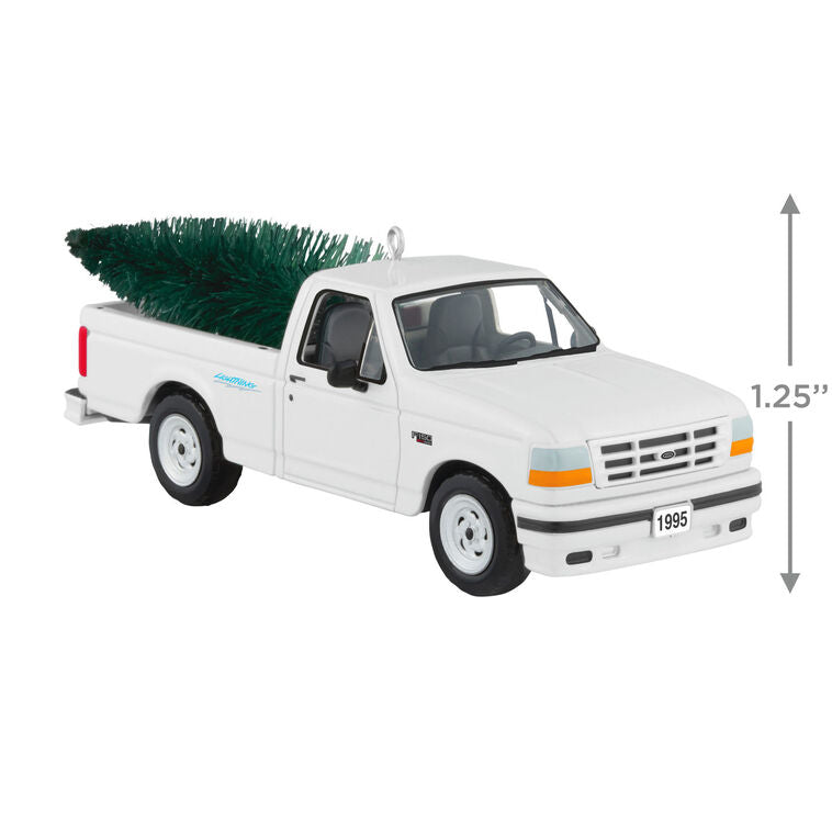 White 1995 Ford SVT Lightning truck ornament with turning wheels and a green bottlebrush Christmas tree in the truck bed.
