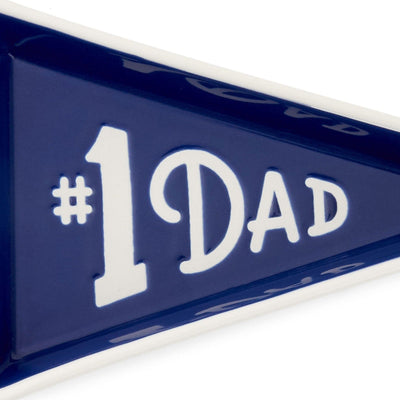 Pennant-shaped ceramic trinket tray with navy blue glaze and white "#1 Dad" message and tie-themed trim.


