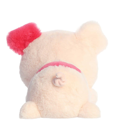 Penelope Pig plush by Aurora, in soft pink with red ear accents, lying belly-down in a cuddly Valentine’s Day pose.
