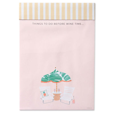 Pink to-do note pad with wine glasses, beach chairs, umbrella, and tropical leaf accents on a striped header.
