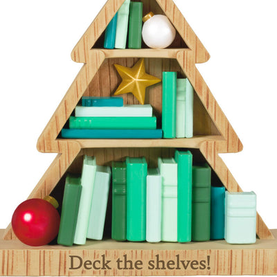 Tree-shaped wooden bookcase ornament filled with green books, red and white ornaments, and gold star accents

