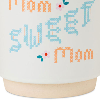 White ceramic mug with “Mom Sweet Mom” in colorful cross-stitch-style lettering and floral accents, oversized handle.