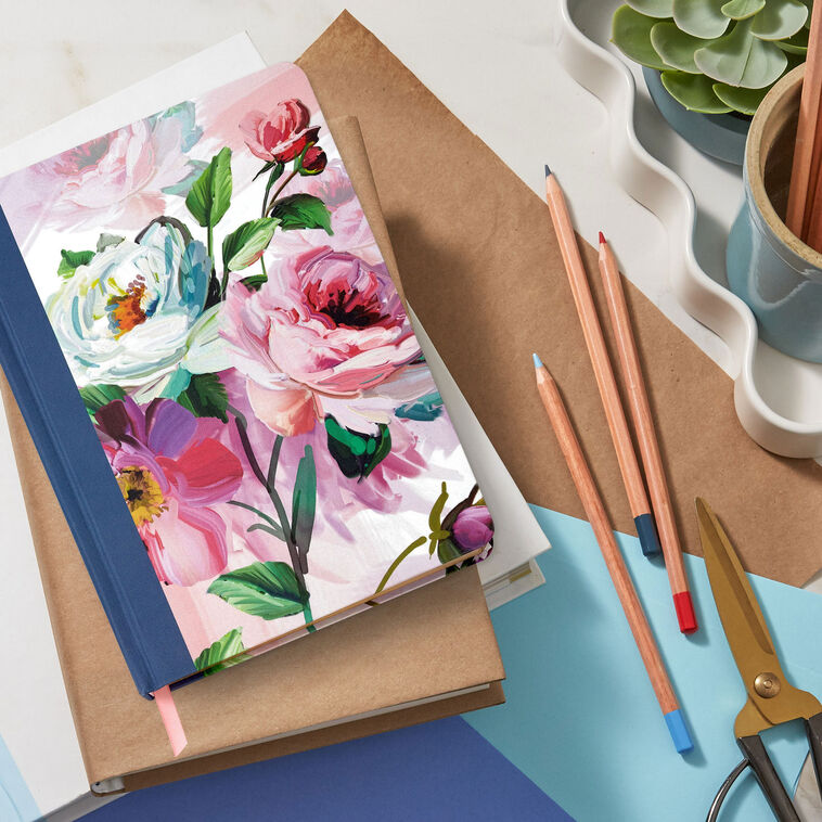 Hardcover journal with purple and pink floral fabric cover, gold-edged pages, and ribbon bookmark.
