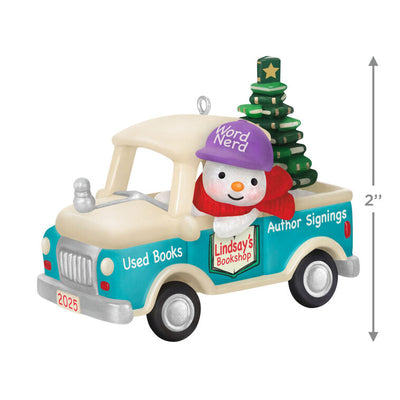 Hallmark Keepsake Holiday Parade 2025 ornament—snowman with “Word Nerd” hat drives bookshop pickup truck hauling Christmas tree made of books
