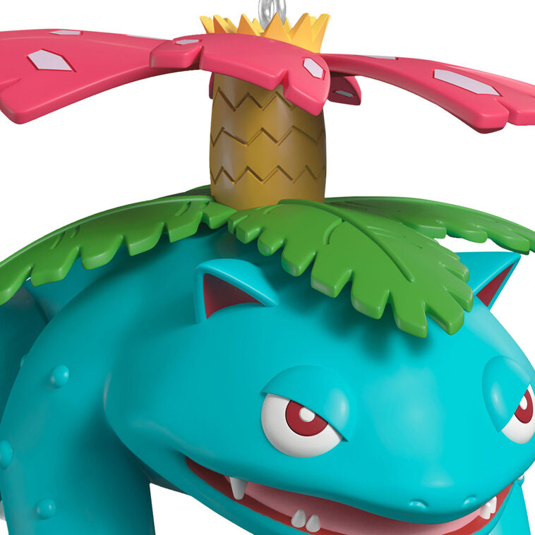 Hallmark Keepsake Pokémon Venusaur ornament with pink blossom on its back, blue-green body, red eyes, and festive Christmas style.