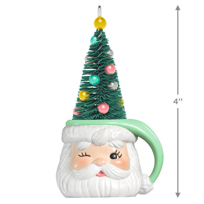 Green stocking hat mug ornament with winking Santa face and pastel ball-decorated bottlebrush tree inside

