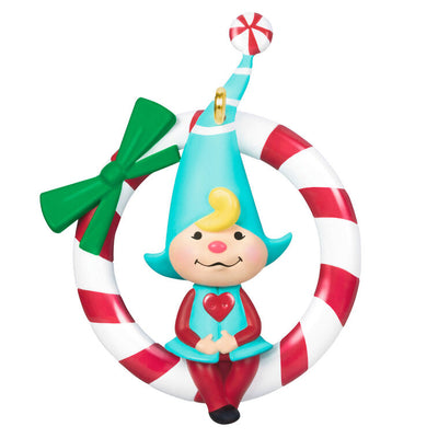 Hallmark Keepsake Sweet Peppermint girl gnome ornament in red and blue, sitting on candy cane wreath with green bow.