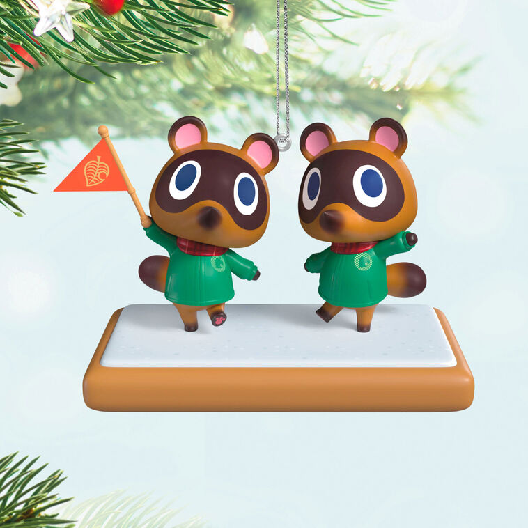 Hallmark Keepsake Nintendo Animal Crossing Timmy and Tommy ornament, twin raccoons with flag, green jackets, red scarves, on wood-style base.