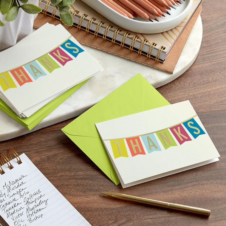 Thank-you cards with colorful pennant banner letters and gold foil on an off-white background.
