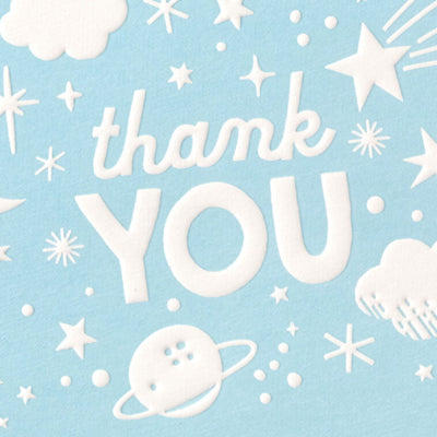 Blue thank-you cards with white embossed designs of a crescent moon, stars, clouds, and planets, shown with matching envelopes in a gift box.
