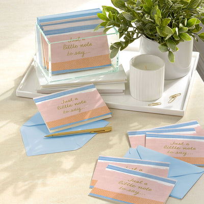 Note cards with pink, blue, and orange brushstroke stripes and gold script reading “Just a little note to say…”, boxed with envelopes.
