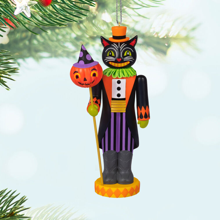 Black cat nutcracker ornament dressed as nobleman with top hat, colorful coat, and pumpkin staff on harlequin base