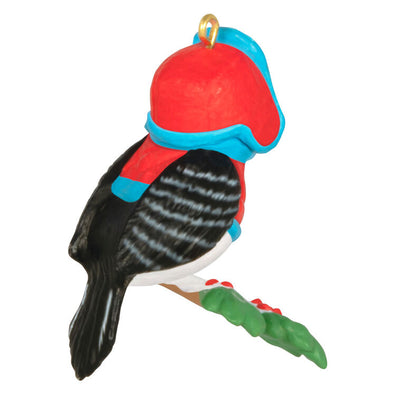 Miniature downy woodpecker ornament in red vest and trapper hat on snowy branch with holly berries, Hallmark Cozy Lil’ Critters
