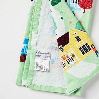 White tea towel printed with a whimsical Stars Hollow map and a central Gilmore Girls quote, includes a loop for hanging.
