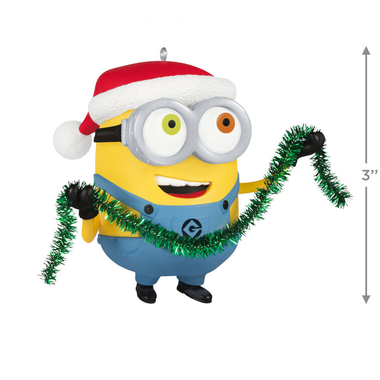 Minion Bob ornament in Santa hat holding green tinsel garland with a big smile