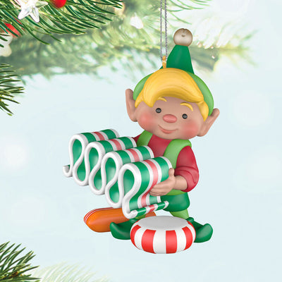 Hallmark Keepsake North Pole Tree Trimmers ornament—Santa’s elf holding old-fashioned ribbon candy, surrounded by hard candies, green hat and red suit
