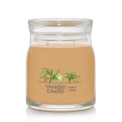 A medium Yankee Candle Sun & Sand jar candle with golden wax and silver lid, evoking a beachy blend of citrus and warm sand scents.