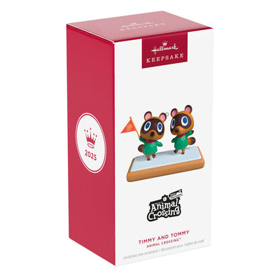 Hallmark Keepsake Nintendo Animal Crossing Timmy and Tommy ornament, twin raccoons with flag, green jackets, red scarves, on wood-style base.