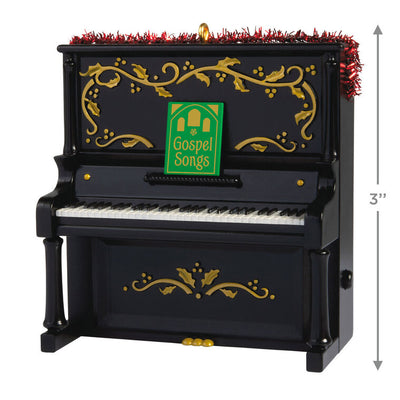 Upright Christmas piano ornament with gold holly accents, tinsel garland, and musical “I’ll Fly Away” gospel choir performa
