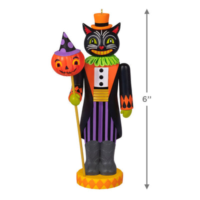 Black cat nutcracker ornament dressed as nobleman with top hat, colorful coat, and pumpkin staff on harlequin base