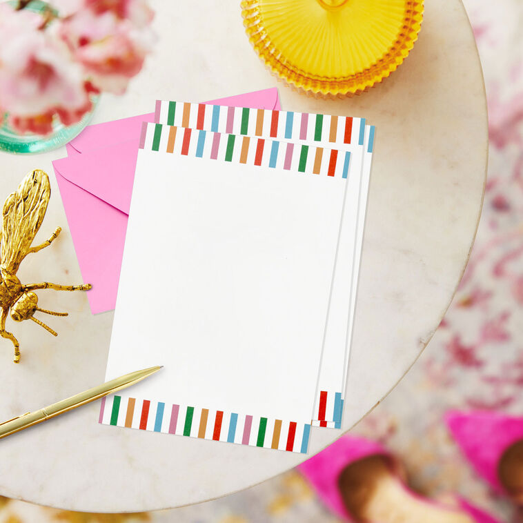 Stationery set with white sheets bordered in bright vertical stripes and colorful envelopes in pink, green, orange, rose, and aqua.
