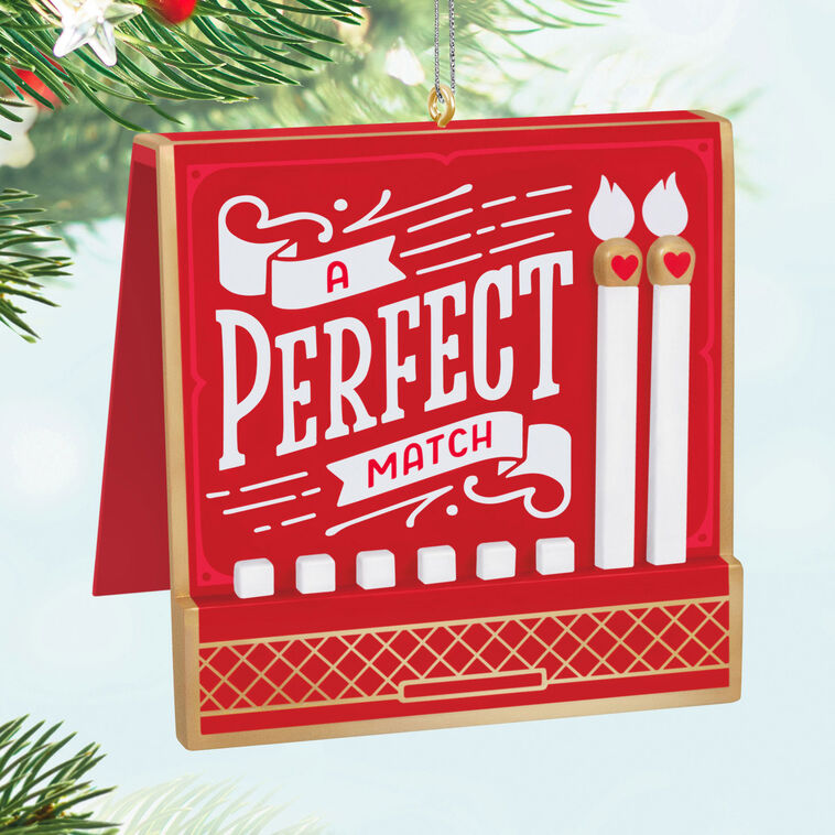 Red and gold matchbook-style ornament with “A Perfect Match” lettering and two heart-accented matchsticks