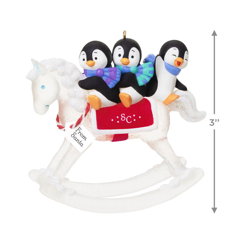 Christmas ornament of playful penguins on a sparkling rocking horse with red and white monogrammed saddle