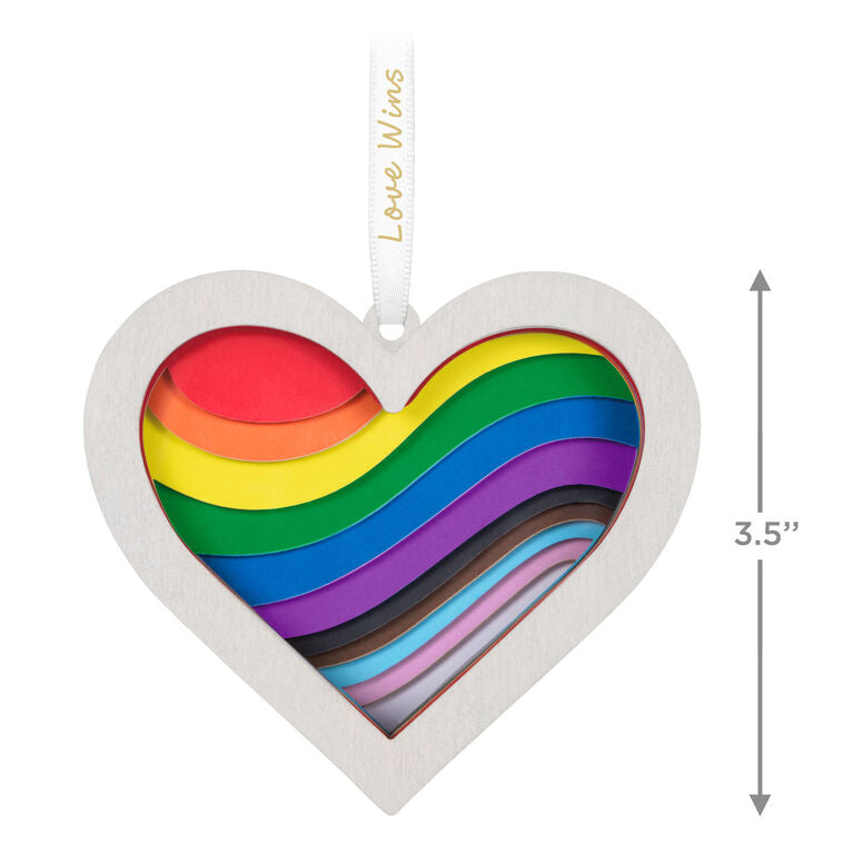 Heart-shaped rainbow papercraft ornament in a whitewashed wood frame with “Love Wins” ribbon for LGBTQIA holiday celebration.