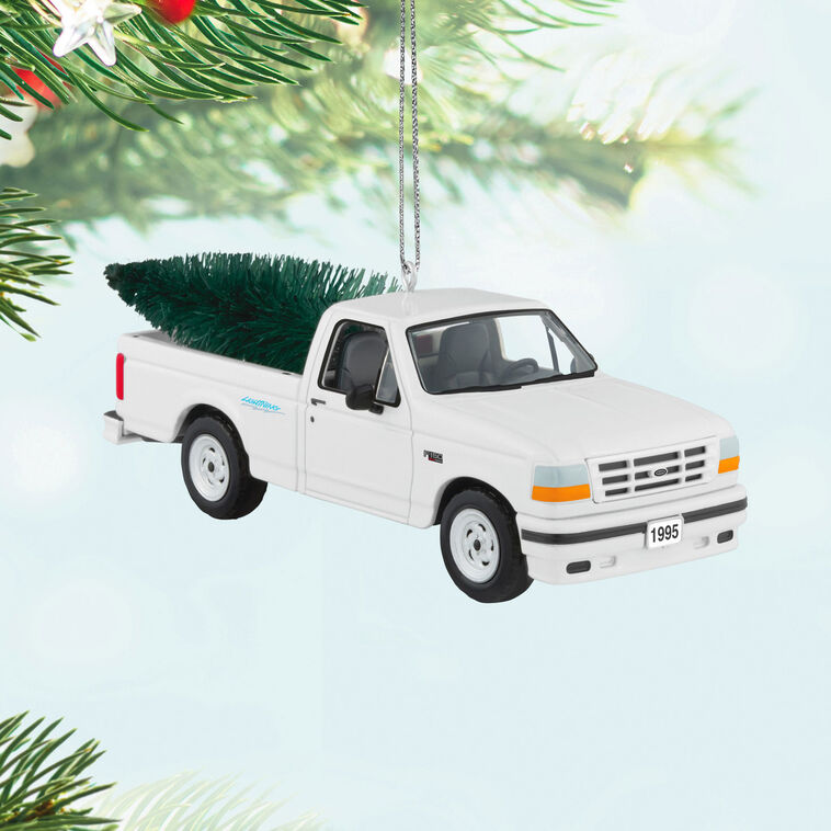 White 1995 Ford SVT Lightning truck ornament with turning wheels and a green bottlebrush Christmas tree in the truck bed.