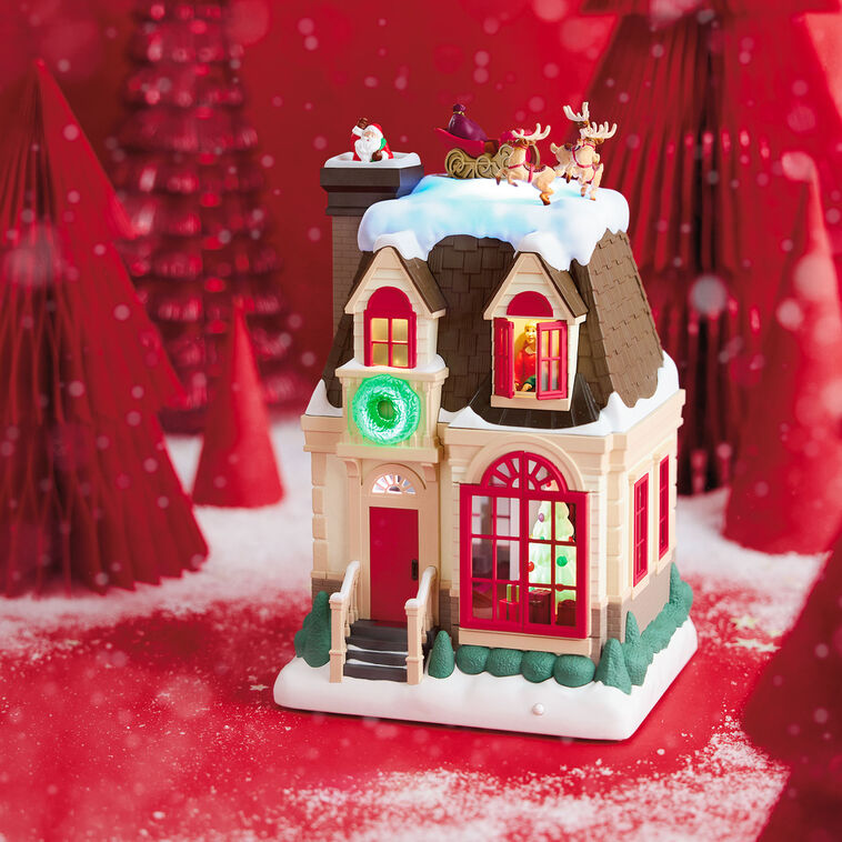 Christmas decoration showing Santa dropping down a chimney with lights, motion, and music from Up on the Housetop

