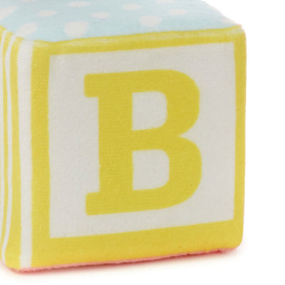 Pastel plush baby block with ABC design and pocket for holding a gift card or mini greeting card, featuring a rattle inside.
