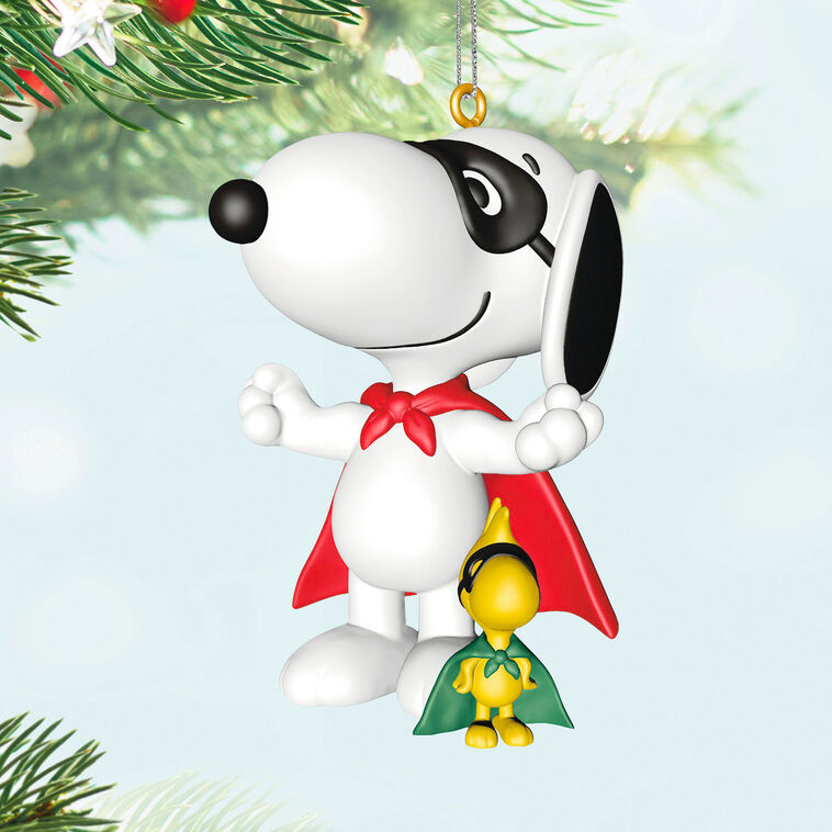 Hallmark Keepsake Peanuts ornament of Snoopy and Woodstock wearing superhero capes and masks, posed as festive holiday heroes.