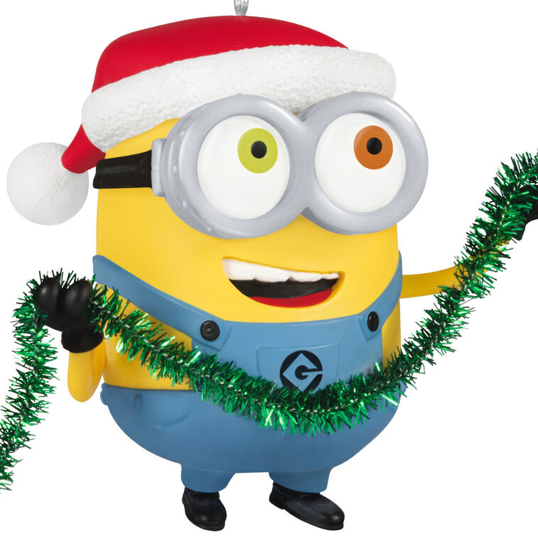 Minion Bob ornament in Santa hat holding green tinsel garland with a big smile