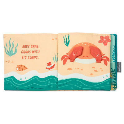 Ocean-themed baby fabric book with sea creature illustrations and tactile features like crinkle paper, squeaker