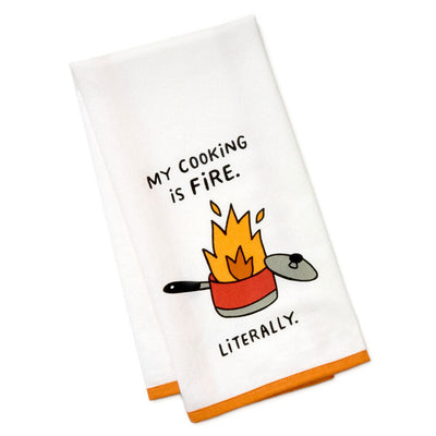 White cotton tea towel with orange border, featuring a flaming pot illustration and the message: “My cooking is fire.