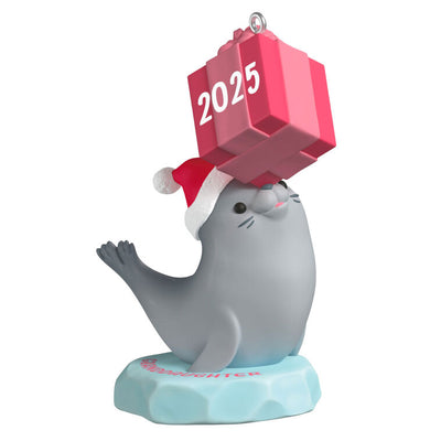 2025 Christmas ornament with gray seal in Santa hat on iceberg, balancing pink present on nose, festive design

