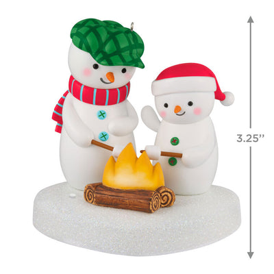 Two snowmen in red and green hats roasting marshmallows over a fire, sparkly base, musical Christmas ornament, battery opera
